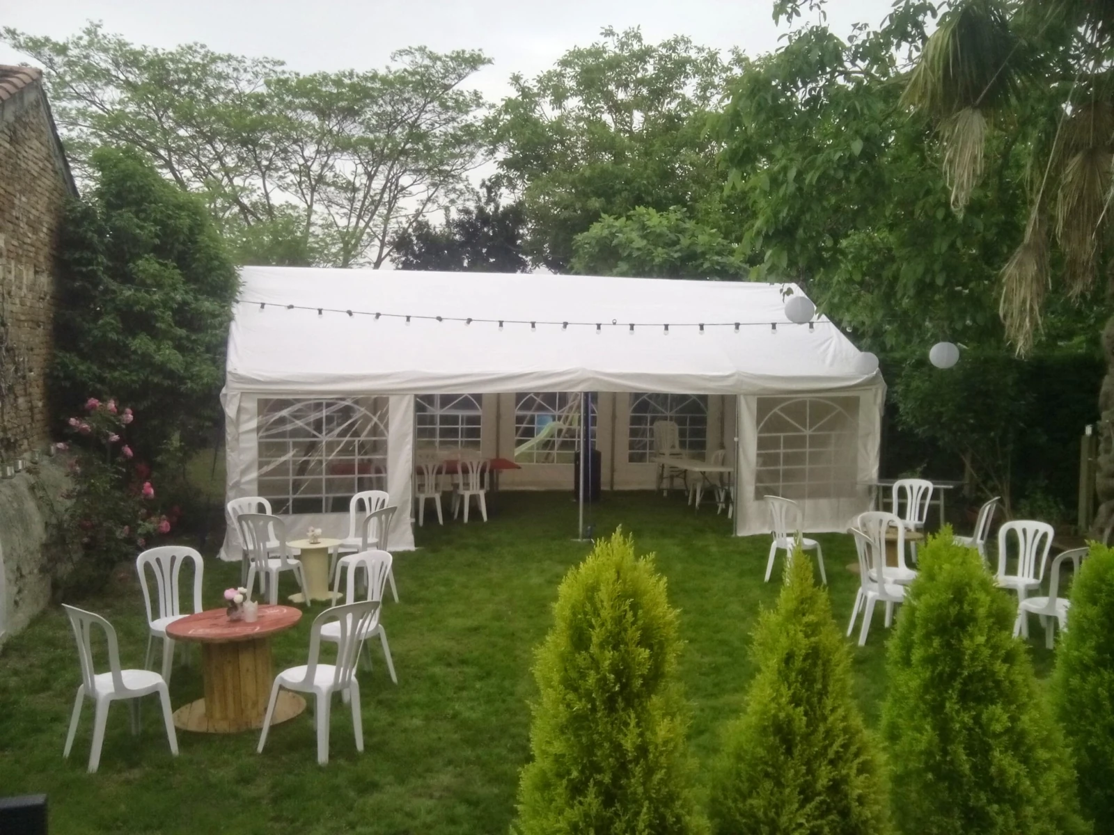Tente de réception blanche installée dans un jardin